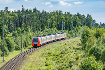 Modern high-speed train approaches to the station at summer morning time.