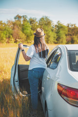 Young woman with white car in the field