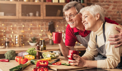Cute senior couple enjoying morning coffee at kitchen