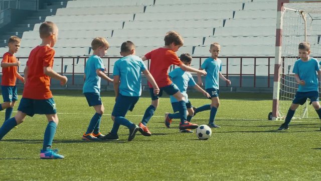 Kids playing soccer on big stadium, dribbling and attacking goal post