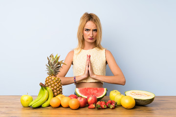 Young blonde woman with lots of fruits pleading