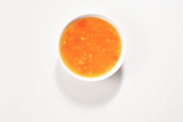 Orange sauce in white plate on white background.