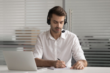 Serious customer support agent wear headset write notes make videocall