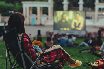 woman eating chips sitting in camp-chair looking movie in open air cinema
