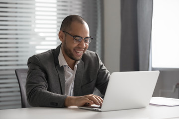 Smiling african businessman working on computer sit at office desk