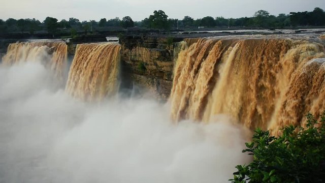 a Locked shot of The Chitrakote Falls: Niagara falls of India. Powerful water rushing over a steep drop into a water mass.