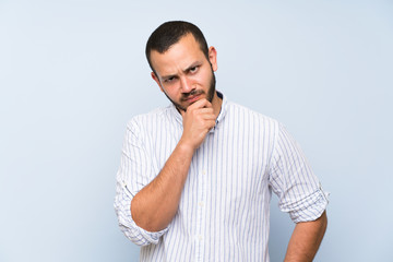 Fototapeta premium Colombian man over isolated blue wall thinking