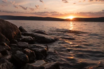 Fotobehang The water at sunset touches the stones © Eduard Vladimirovich