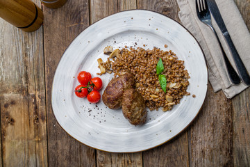 beef cutlets with buckwheat and mushrooms on a plate on wooden table