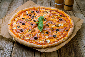 Capricciosa pizza with artichokes on wooden table