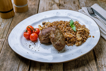 beef cutlets with buckwheat and mushrooms on a plate on wooden table