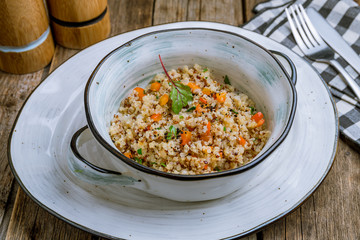 Quinoa side dish with onions and vegetables on wooden table