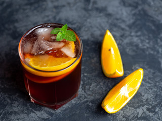 Negroni cocktail with ice and orange on dark background