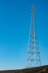 Electric company power line tower above a burn after a prescribed grass fire to reduce wildfire danger