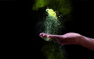 Hand holding yellow holi powder for color festival on black