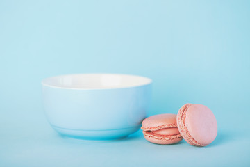 Raspberry pastel pink macarons next to a blue bowl