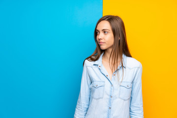 Obraz premium Young woman over colorful background looking side