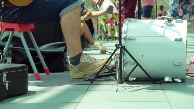 Close up drummer legs on the bass drum pedal outdoors on a sunny day. Street musician playing in the park. slow motion