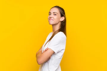 Fotobehang Young woman over isolated yellow background laughing © luismolinero