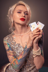 Blonde woman with a beautiful hairstyle and perfect make-up is posing with playing cards in her hands. Casino, poker.