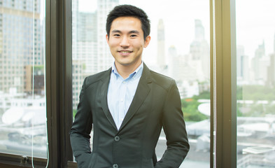 Fototapeta premium An asian business man is standing beside the window