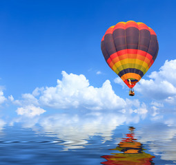Obraz premium Colorful Hot Air Balloons in Flight over blue sky with water reflection