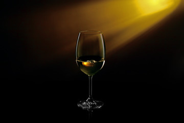 Glass of white wine on black to yellow background. Concept studio shot.