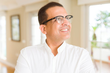 Middle age man wearing glasses smiling to the camera at home
