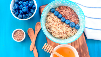 Healthy breakfast ingredients. Buckwheat blueberries mint honey on white wooden background, top view, copy space