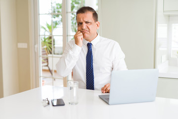 Middle age business man working with computer laptop looking stressed and nervous with hands on mouth biting nails. Anxiety problem.