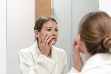 Obraz na płótnie Canvas Woman in bathrobe looking in mirror at bathroom