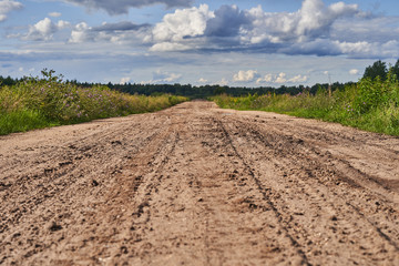 Fototapeta na wymiar Old wide sandy road with a rolled track after the rain