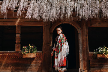 Girl in the Ukrainian embroidered dress poses near the house