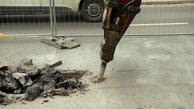 Close-up of hydraulic arm hammer breaks the asphalt on the road. Prores, slow motion