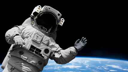 astronaut waving during a spacewalk in orbit of planet Earth 