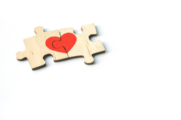 Red heart is drawn on the pieces of the wooden puzzle lying next to each other isolated on white background. Love concept. St. Valentine day. Copy space.