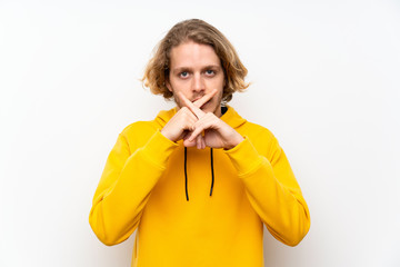 Blonde man with  sweatshirt over white wall showing a sign of silence gesture