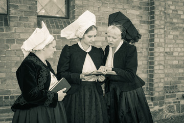 3 Wendinnen treffen sich in ihrer Kirchgangstracht vor der Kirche