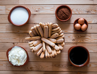 Natural ingredients to prepare a sweet cheesecake, the tiramisu. Wooden table as background. A special dessert for a party