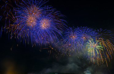 Colorful fireworks. Fireworks are a class of explosive pyrotechnic devices used for entertainment purposes. Visible noise due to low light, soft focus, shallow DOF, slight motion blur