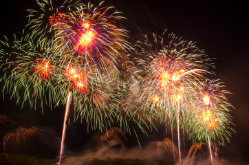 Colorful fireworks. Fireworks are a class of explosive pyrotechnic devices used for entertainment purposes. Visible noise due to low light, soft focus, shallow DOF, slight motion blur