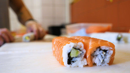 Close-up of professional chef's hands in transparent gloves making sushi and rolls in a restaurant kitchen. Japanese traditional food. Preparation process. Concept of: Preparing, Rolling, Salamon.