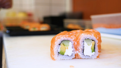 Close-up of professional chef's hands in transparent gloves making sushi and rolls in a restaurant kitchen. Japanese traditional food. Preparation process. Concept of: Preparing, Rolling, Salamon.
