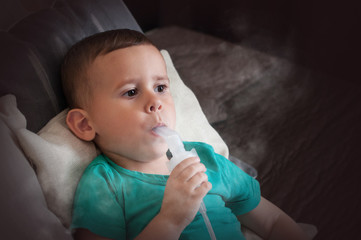 Three year old boy making inhalation with nebulizer at home.