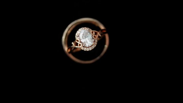 Camera circulating around wedding golden rings whith diamonds on dark background close-up