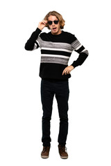 Full-length shot of Blonde man with glasses and surprised over isolated white background