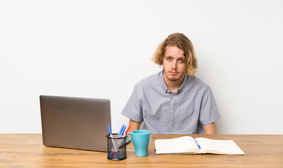 Blonde man with a laptop with sad and depressed expression