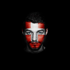 Flag of Switzerland painted on a face of a man on black background.