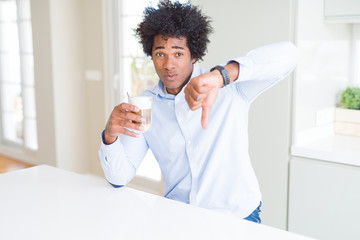 African American man with afro hair drinking a cup of coffee with angry face, negative sign showing...
