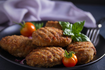 Delicious homemade beef burgers or cutlets (patties) with vegetables on black plate. overhead, horizontal